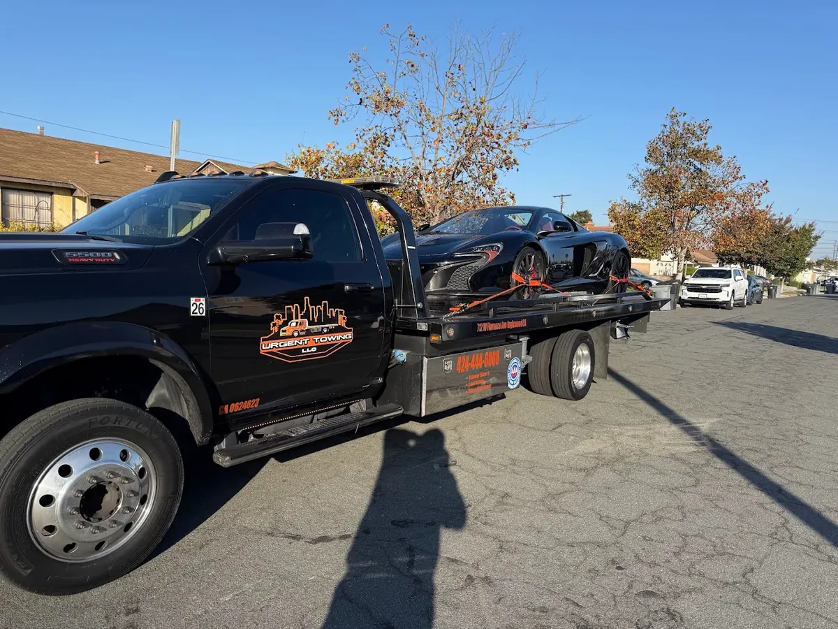 Black Urgent Towing Ram flatbed on a residential street