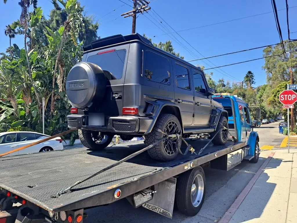 Blue Urgent Towing flatbed loading an SUV with the bed tilted