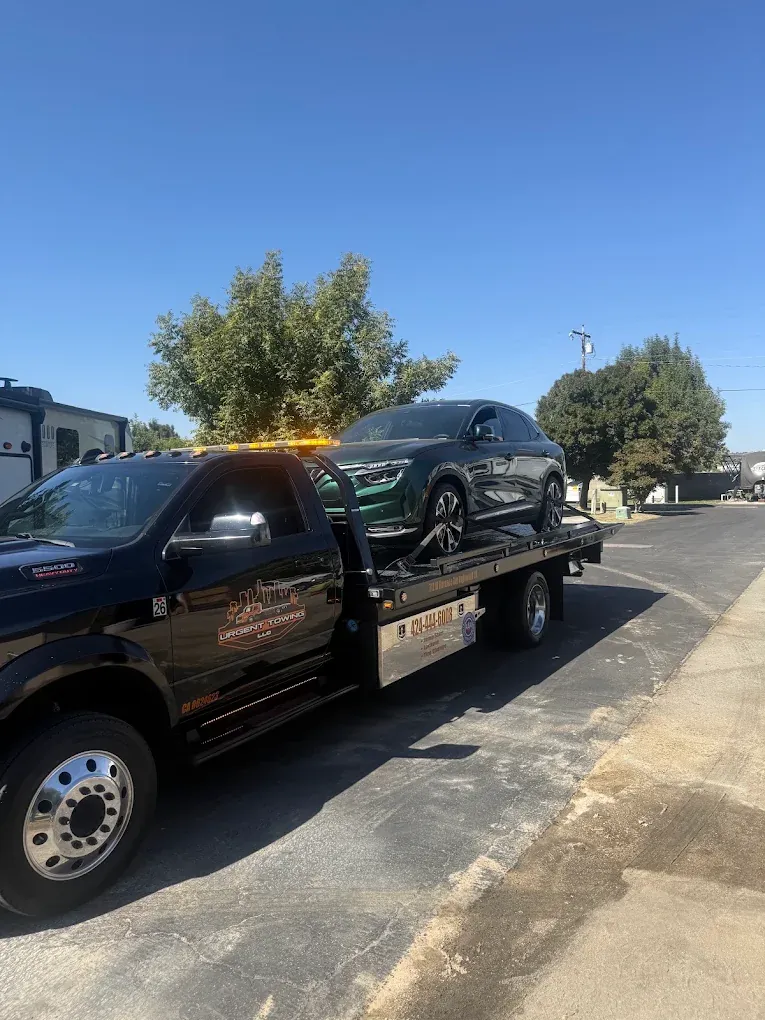 Black Urgent Towing Ram flatbed carrying an SUV
