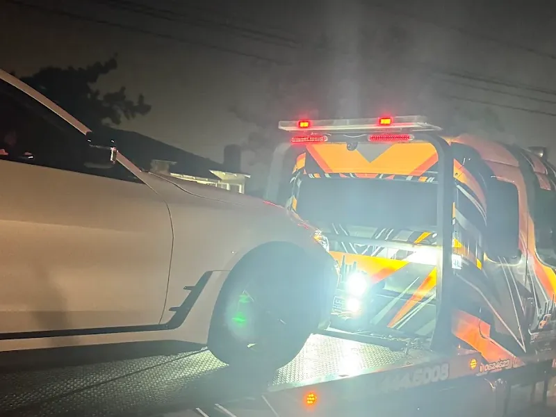 Urgent Towing flatbed loading a car at night