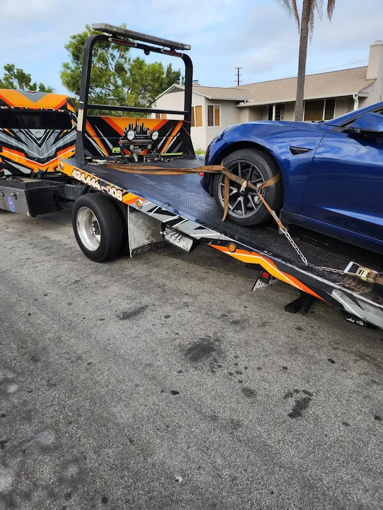 Blue Tesla being winched onto a tilted Urgent Towing flatbed