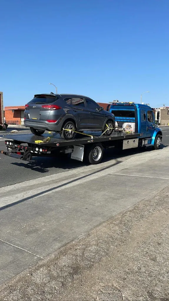 Blue Urgent Towing flatbed carrying an SUV
