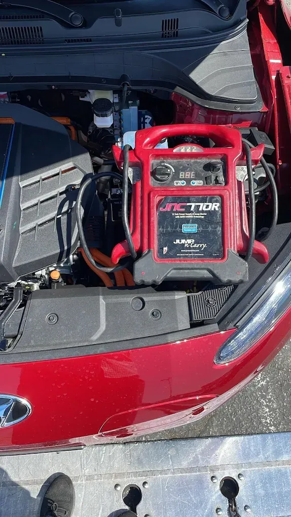 Red portable jump starter connected to a car battery