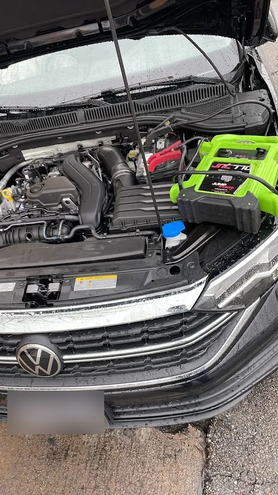 Green portable jump starter connected under the hood of a Volkswagen