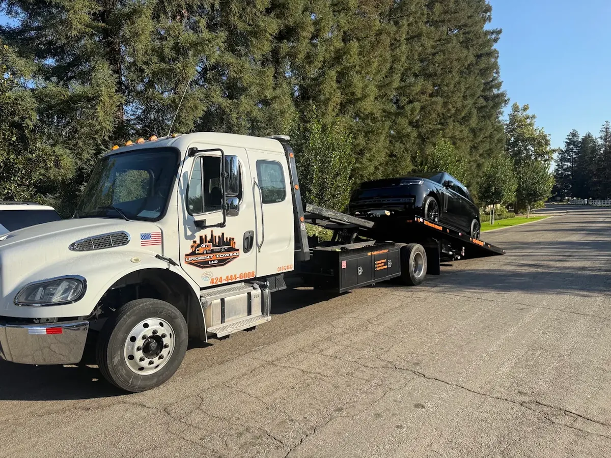 White Urgent Towing flatbed loading a car with the bed tilted