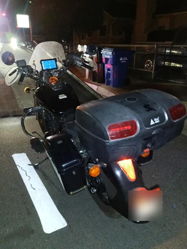 Black touring motorcycle waiting at the curb for a night pickup