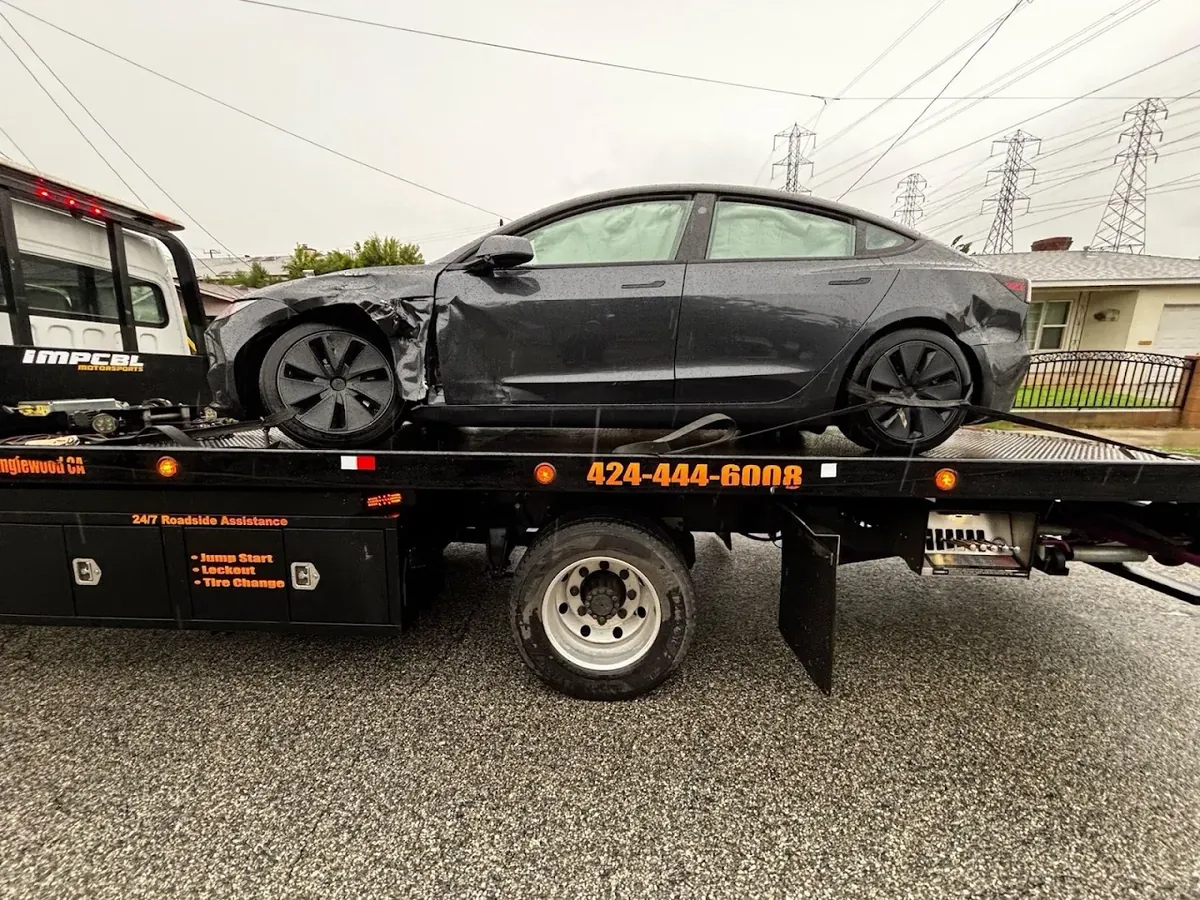 Gray Tesla with front collision damage secured on an Urgent Towing flatbed