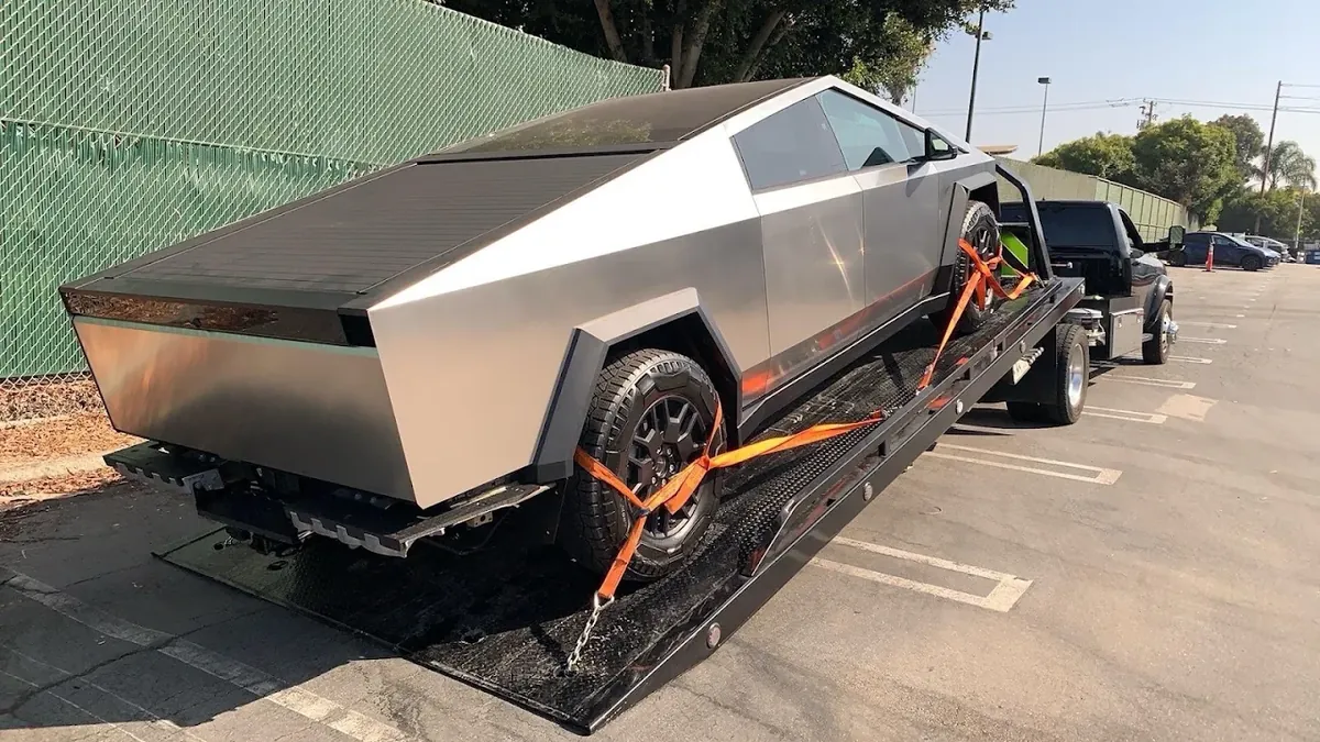 Tesla Cybertruck tied down with orange wheel straps on a flatbed