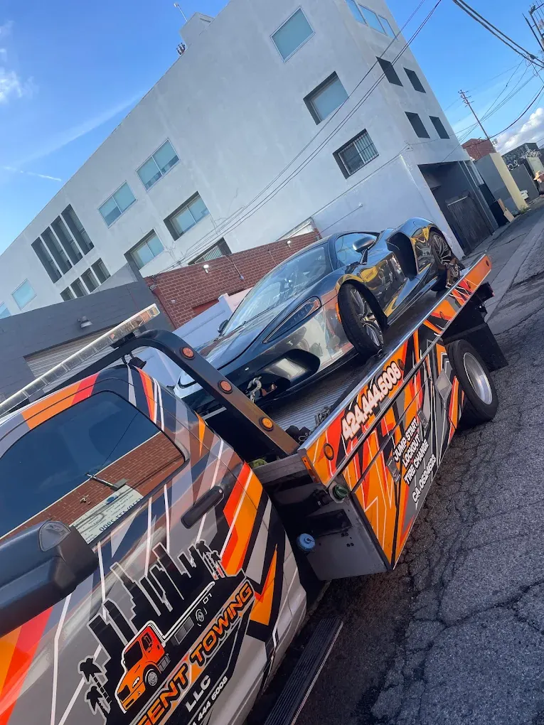 Urgent Towing flatbed with a sports car; the truck side lists jump start, lockout and tire change