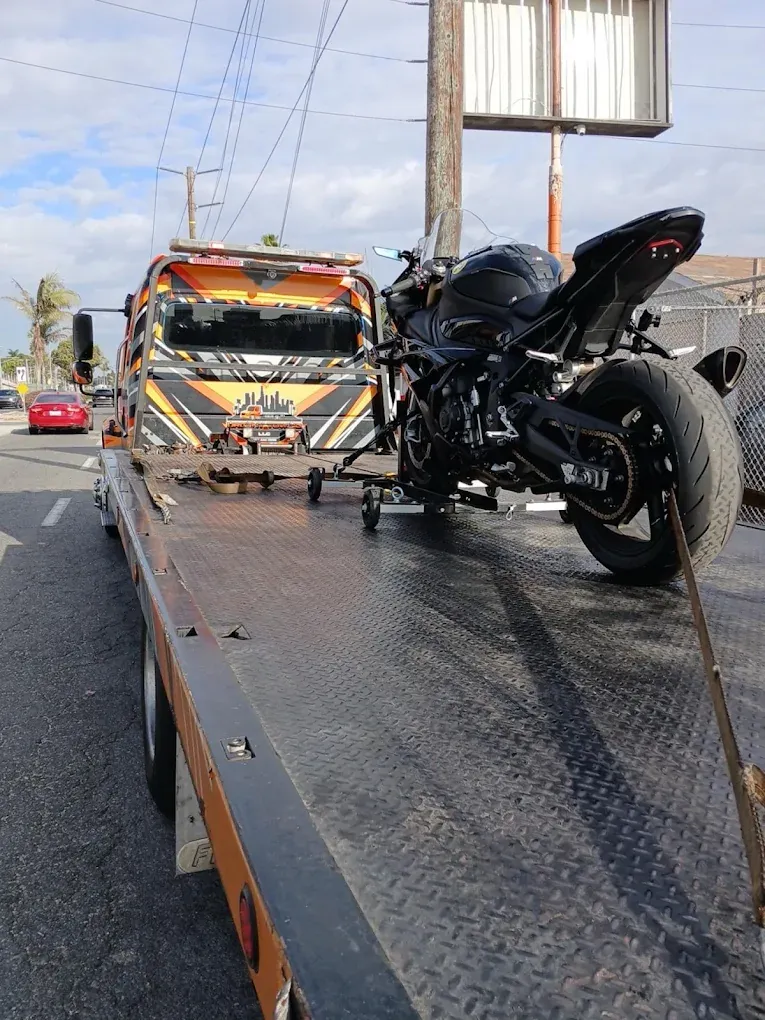 Black sport bike strapped upright on an Urgent Towing flatbed