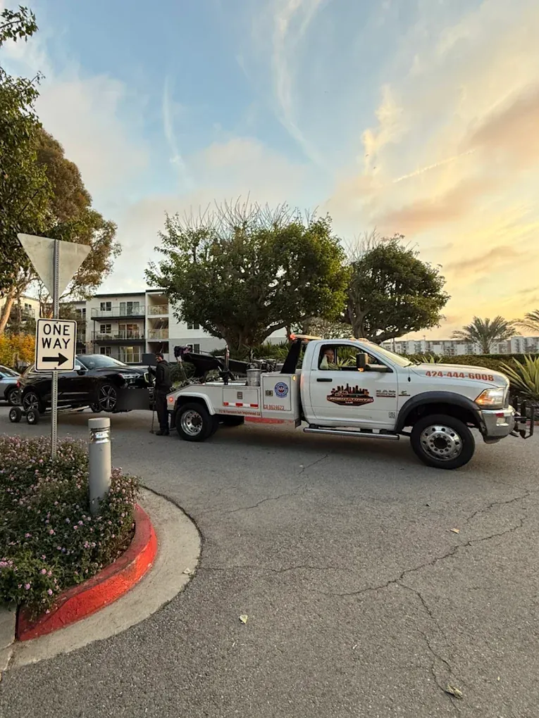 Urgent Towing wheel-lift truck outside an apartment complex at sunset