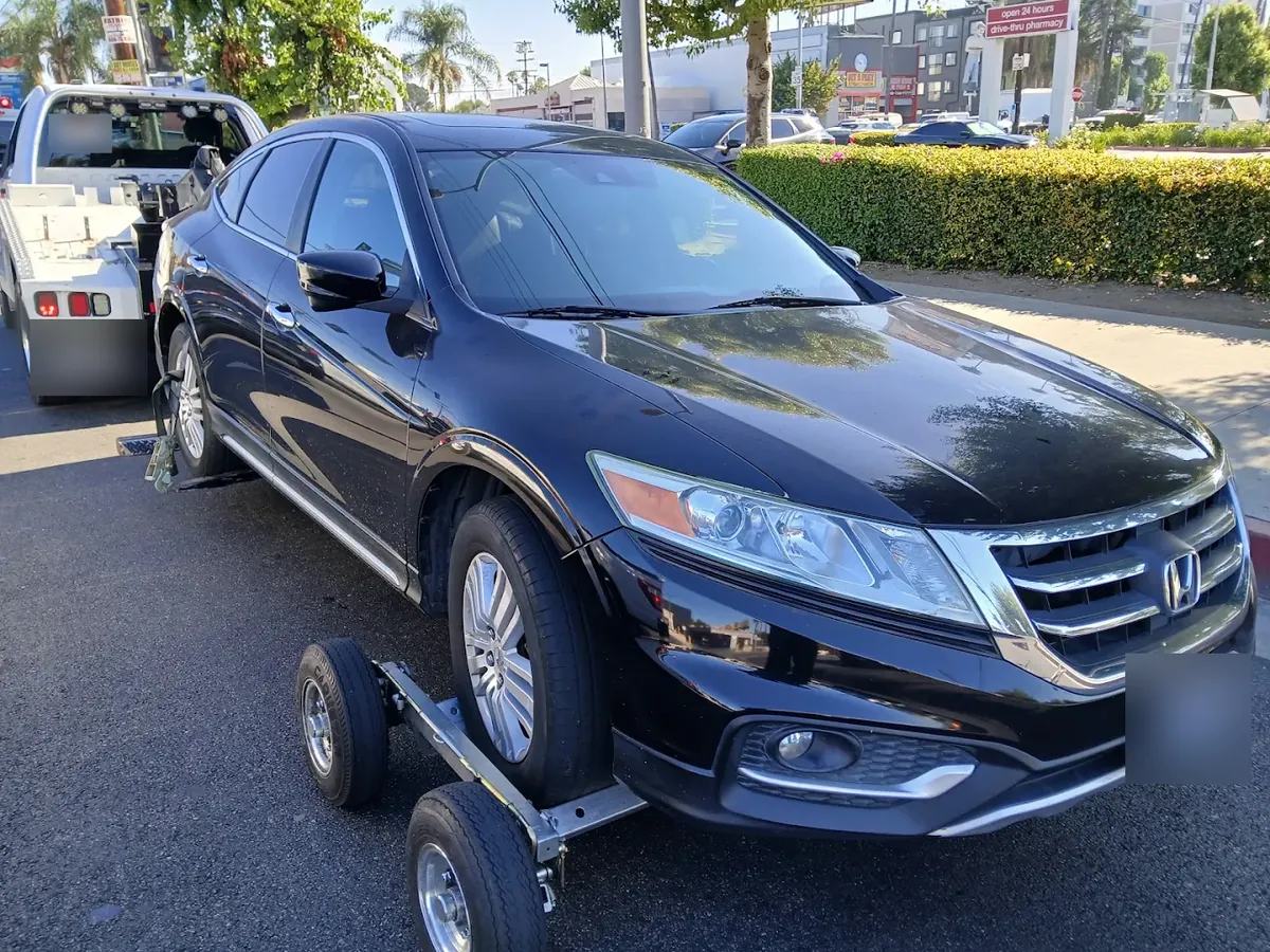 Wheel-lift tow with wheel dollies under a black SUV